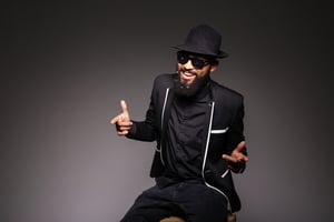 Cheerful afro american man in stylish cloth and glasses posing over black background
